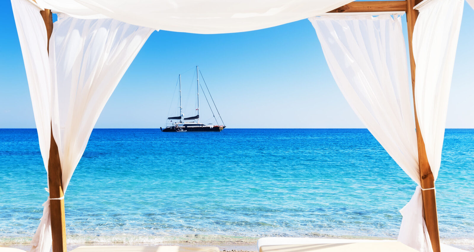 View of the beautiful beach through a Balinese bed